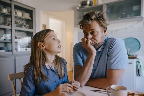 Daughter talking to father in kitchen at home